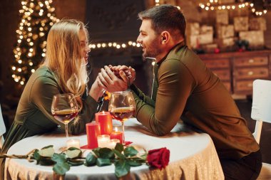 Ellerinden tutarak. Genç ve güzel çift evde romantik bir akşam yemeği yiyor..