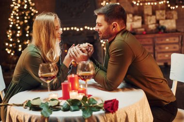 Ellerinden tutarak. Genç ve güzel çift evde romantik bir akşam yemeği yiyor..