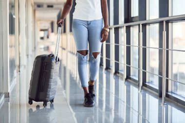 Genç Afro-Amerikan kadın yolcunun parçacık görüntüsü havaalanında bagajlı günlük giysiler içinde..