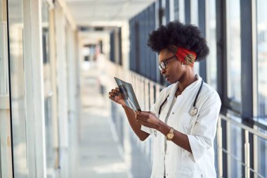 Beyaz üniformalı genç Afrikalı Amerikalı kadın doktor röntgene bakıyor..