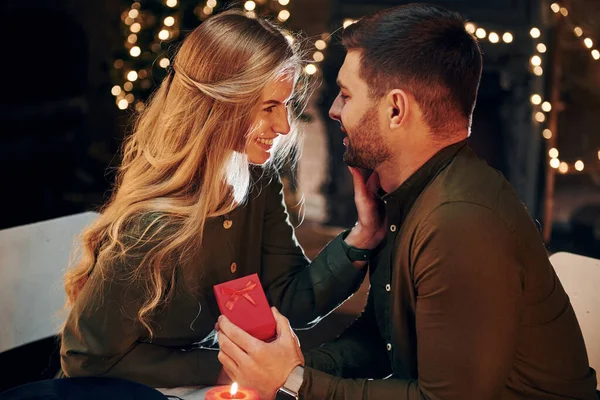 Adamın elinde hediye kutusu var. Evlenme teklifi yapar. Genç ve güzel çift evde romantik bir akşam yemeği yiyor..