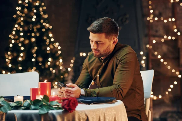 Genç yakışıklı adam masada oturur ve restoranda romantik bir akşam yemeği için kız arkadaşını bekler..