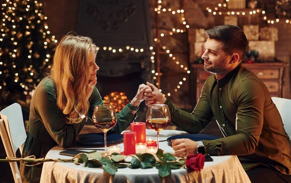 Ellerinden tutarak. Genç ve güzel çift evde romantik bir akşam yemeği yiyor..