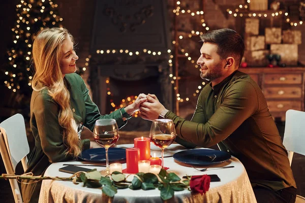 Ellerinden tutarak. Genç ve güzel çift evde romantik bir akşam yemeği yiyor..