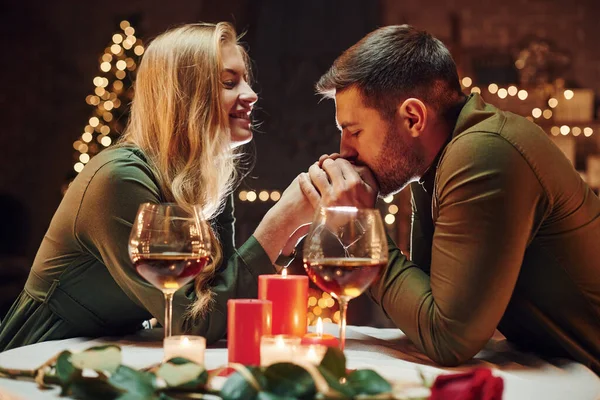 Ellerinden tutarak. Genç ve güzel çift evde romantik bir akşam yemeği yiyor..