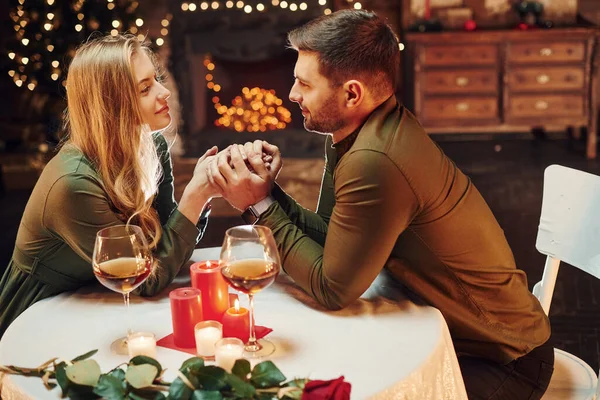 Ellerinden tutarak. Genç ve güzel çift evde romantik bir akşam yemeği yiyor..