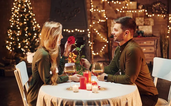 捧着美丽的红玫瑰 年轻貌美的夫妻在室内共进浪漫晚餐 — 图库照片