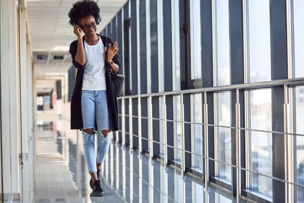 Genç Afrikalı Amerikalı kadın yolcu havaalanında kulaklıkla müzik dinliyor..