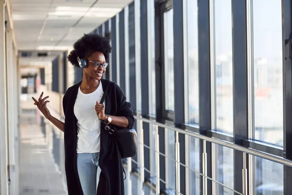 Genç Afrikalı Amerikalı kadın yolcu havaalanında kulaklıkla müzik dinliyor..