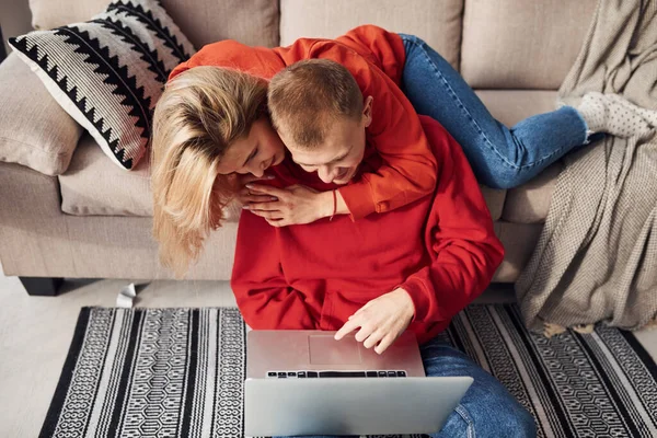 Bacaklarındaki dizüstü bilgisayarı kullanarak. Genç ve sevimli çift hafta sonunu ve tatilleri birlikte geçiriyorlar..