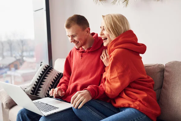 Bacaklarındaki dizüstü bilgisayarı kullanarak. Genç ve sevimli çift hafta sonunu ve tatilleri birlikte geçiriyorlar..