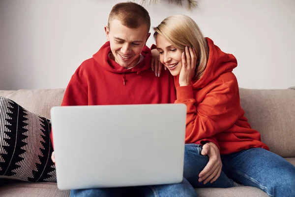 Bacaklarındaki dizüstü bilgisayarı kullanarak. Genç ve sevimli çift hafta sonunu ve tatilleri birlikte geçiriyorlar..