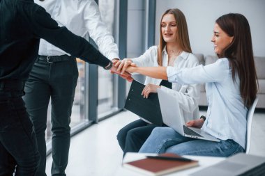 Bir grup başarılı genç takım yumruklaşıyor ve ofiste başarıyı kutluyor..