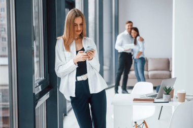 Ofiste birlikte çalışan ve iletişim kuran başarılı genç bir ekip grubunun önünde telefonu olan bir kadın..