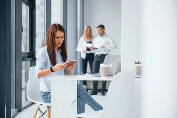 職場で屋内で一緒に働くと通信する若い成功したチームのグループの前に座っているラップトップを持つ女性 — ストック写真
