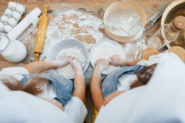 Mutfakta yemek hazırlayan mavi şef üniformalı iki küçük kızın manzarası..