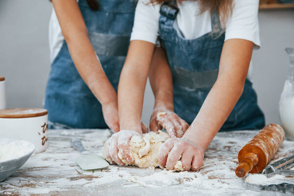 Close up view of two little girls in blue chef uniform that preparing food on the kitchen.