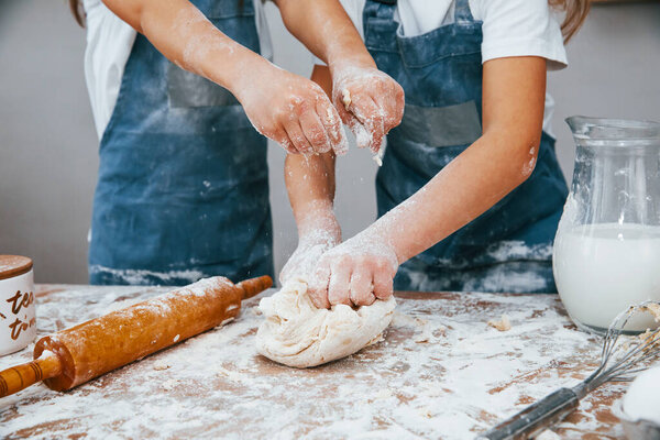Close up view of two little girls in blue chef uniform that preparing food on the kitchen.