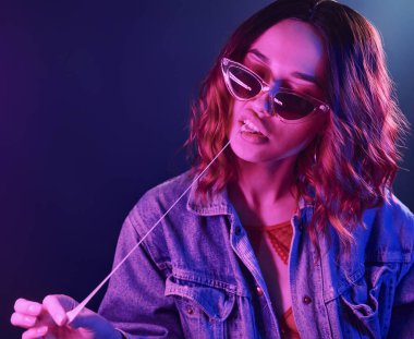 Gözlüklü genç kızın portresi. Stüdyoda kırmızı ve mavi neon sakızlı..