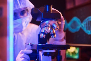 Maskeli hemşire ve beyaz üniformalı hemşire laboratuarda bilgisayar, mikroskop ve tıbbi ekipmanla Coronavirus aşısını arıyor..