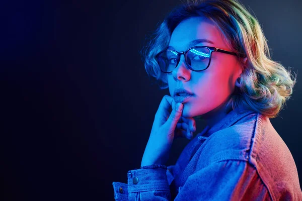 Gözlüklü, yeşil saçlı, stüdyoda kırmızı ve mavi ışıklı genç bir kızın portresi..