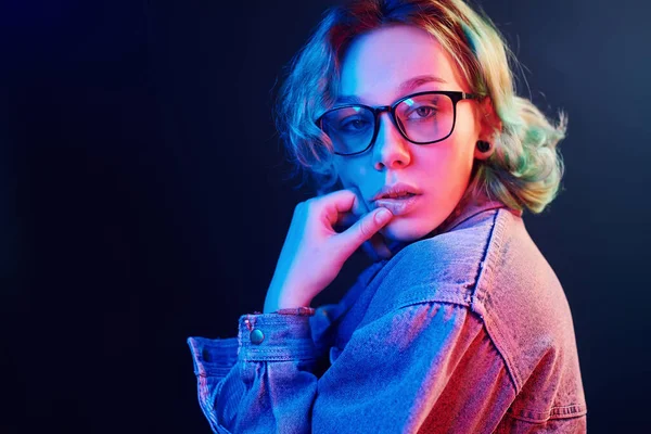 Gözlüklü, yeşil saçlı, stüdyoda kırmızı ve mavi ışıklı genç bir kızın portresi..