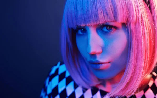 Portrait of young girl with blond hair in red and blue neon in studio.