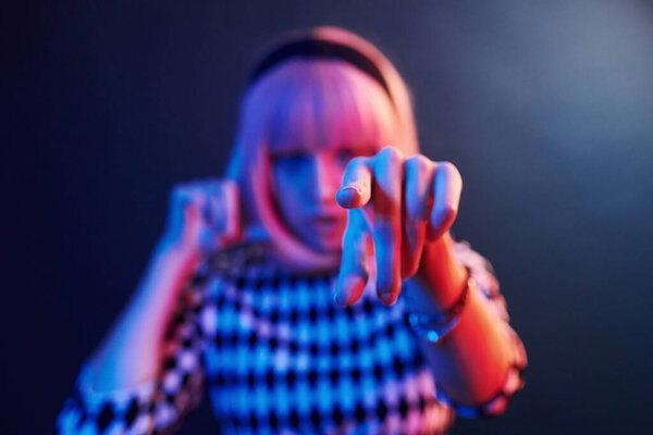 Портрет молодой девушки с светлыми волосами в красно-синем неоне в студии.