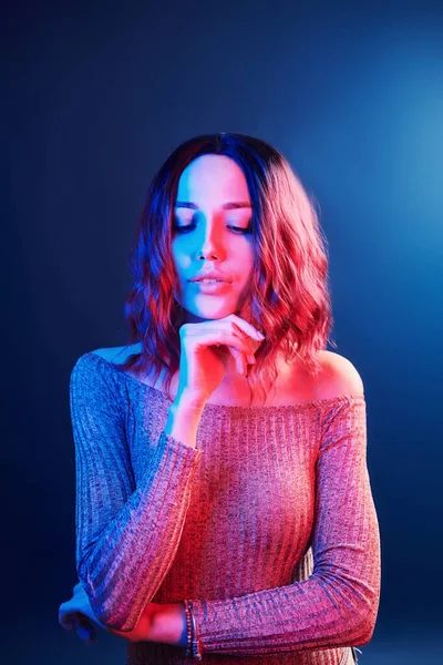 Portrait of young girl with curly hair in red and blue neon in studio.