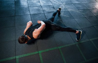 Spor kıyafetleri içindeki güçlü genç adam spor salonunda şınav çekiyor..