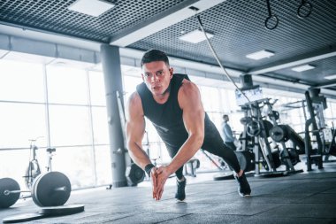 Spor kıyafetleri içindeki güçlü genç adam spor salonunda şınav çekiyor..