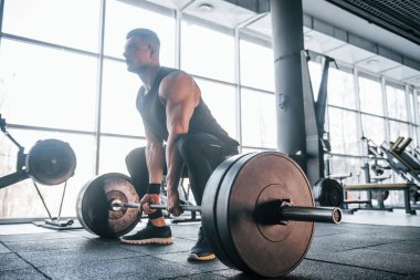 Spor kıyafetleri içindeki güçlü genç adam spor salonunda ağır toplarla egzersiz yapıyor..