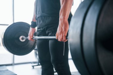 Spor kıyafetleri içindeki güçlü genç adam spor salonunda ağır toplarla egzersiz yapıyor..