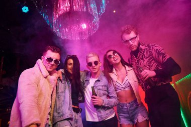 Kameraya poz veriyorum. Gençler gece kulübünde renkli lazer ışıklarıyla eğleniyorlar..