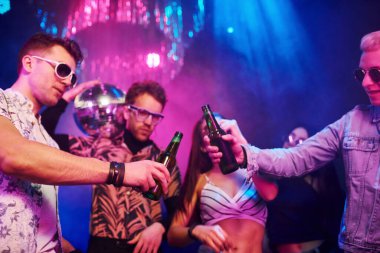 Kutlama ve şişelere alkolle vurmak. Gençler gece kulübünde renkli lazer ışıklarıyla eğleniyorlar..