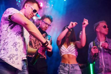 Kutlama ve şişelere alkolle vurmak. Gençler gece kulübünde renkli lazer ışıklarıyla eğleniyorlar..