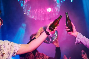 Kutlama ve şişelere alkolle vurmak. Gençler gece kulübünde renkli lazer ışıklarıyla eğleniyorlar..