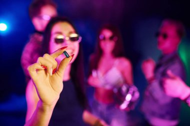 Kadının ellerine uyuşturucu hapıyla yakından bak. Gençler gece kulübünde renkli lazer ışıklarıyla eğleniyorlar..