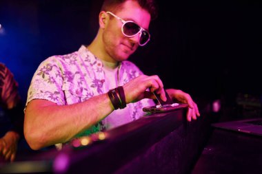 Şık elbiseli ve güneş gözlüklü genç adam gece kulübünde uyuşturucu kokluyor..