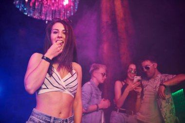 Gençler gece kulübünde renkli lazer ışıklarıyla eğleniyorlar..