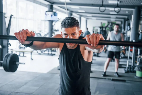 Spor kıyafetleri içindeki güçlü genç adam spor salonunda spor yapıyor. Ara veriyoruz..