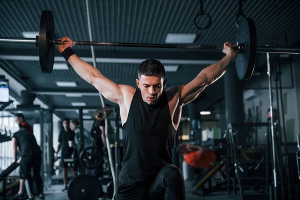 Spor kıyafetleri içindeki güçlü genç adam spor salonunda ağır toplarla egzersiz yapıyor..