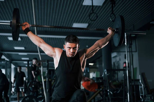 Spor kıyafetleri içindeki güçlü genç adam spor salonunda ağır toplarla egzersiz yapıyor..