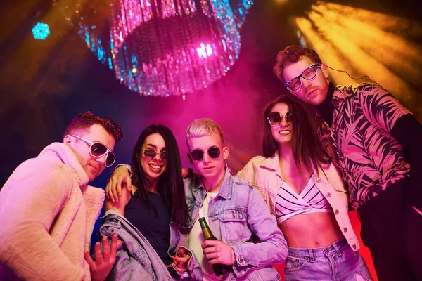 Kameraya poz veriyorum. Gençler gece kulübünde renkli lazer ışıklarıyla eğleniyorlar..