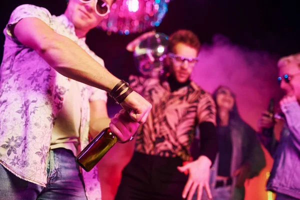 Kutlama ve şişelere alkolle vurmak. Gençler gece kulübünde renkli lazer ışıklarıyla eğleniyorlar..