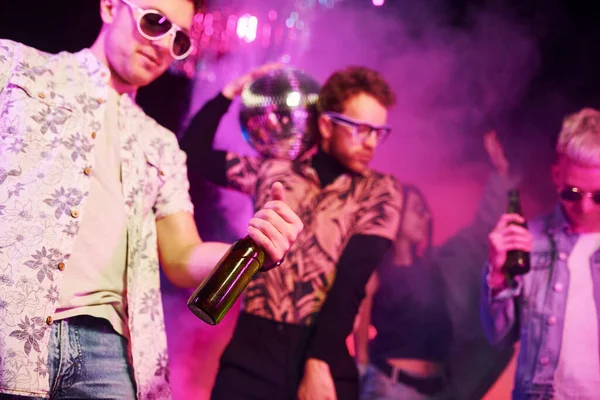 Kutlama ve şişelere alkolle vurmak. Gençler gece kulübünde renkli lazer ışıklarıyla eğleniyorlar..