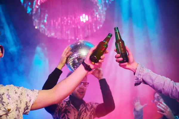 Kutlama ve şişelere alkolle vurmak. Gençler gece kulübünde renkli lazer ışıklarıyla eğleniyorlar..