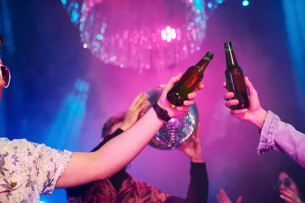 Kutlama ve şişelere alkolle vurmak. Gençler gece kulübünde renkli lazer ışıklarıyla eğleniyorlar..