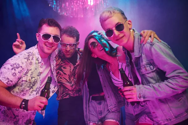 Ellerinde bira şişeleriyle. Gençler gece kulübünde renkli lazer ışıklarıyla eğleniyorlar..