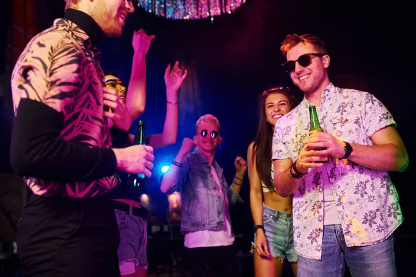 Gençler gece kulübünde renkli lazer ışıklarıyla eğleniyorlar..